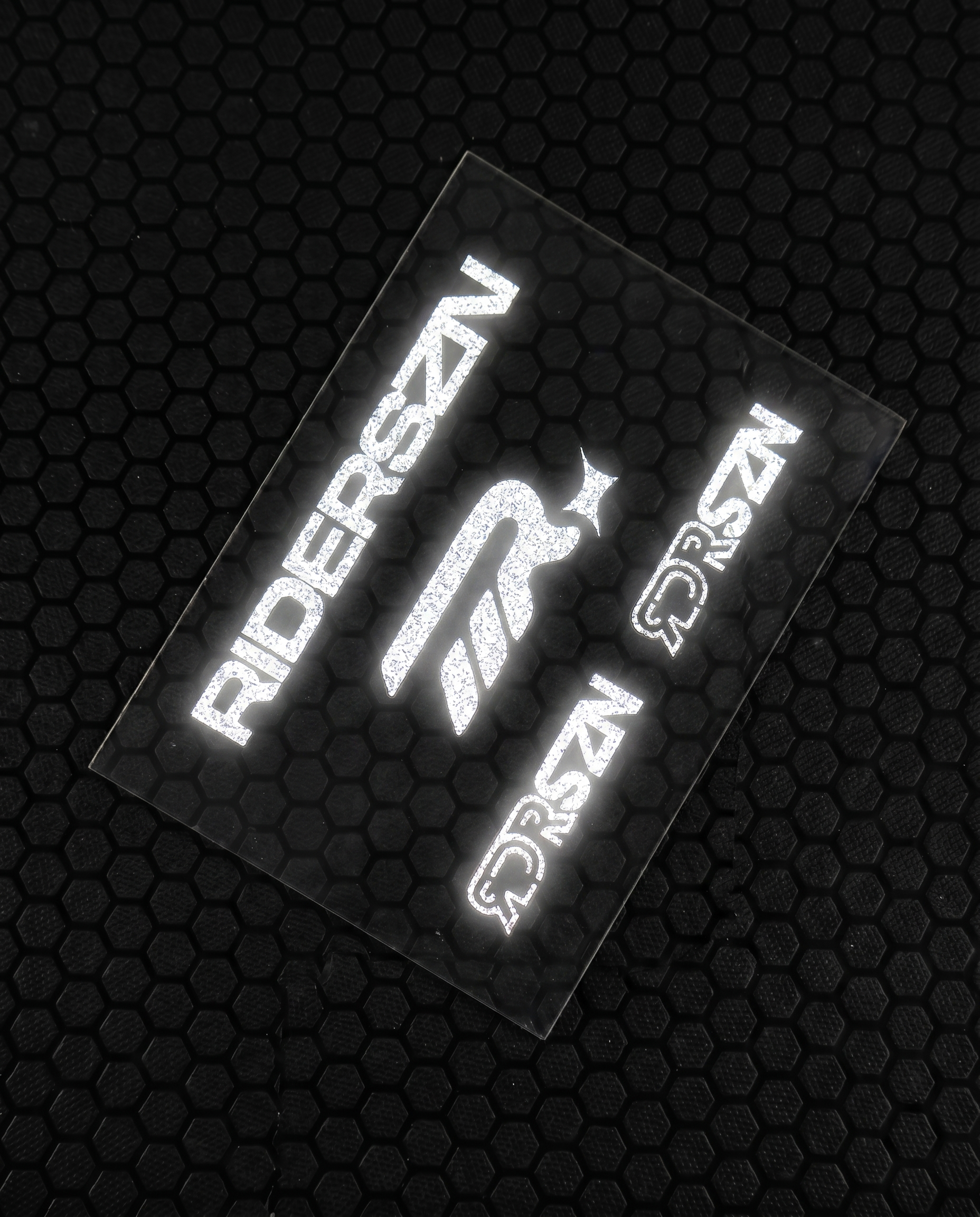 Reflective stickers with 'RIDERSZN' and RDRSZN logo on a textured black background